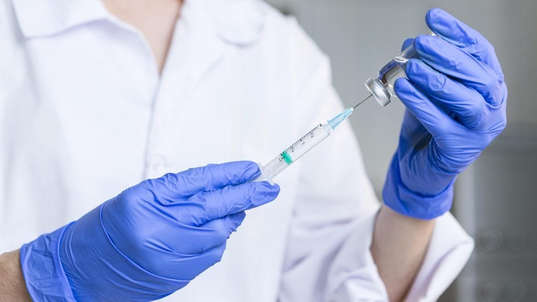 female-researcher-with-safety-glasses-and-gloves-holding-syringe