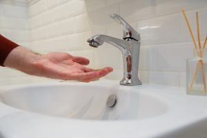 Man holding his hand under opened tap without water