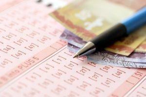 Pen with Brazilian money bills on blank of lottery game. Concept of luck and gambling in Brazil