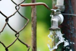 Close up of grunge brass faucet on green bokeh background. Water shortage and earth day concept.