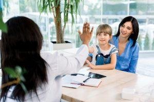 Happy Caucasian child little girl give high five to african woman pediatrician welcome little