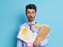 Shocked male student has papers with written math solution greatly surprised to have deadline wears